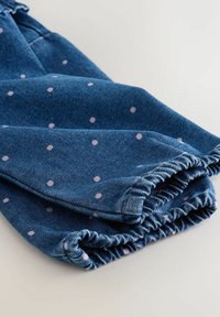 Blaue Denim-Kleidung mit elastischen Bündchen, die durchgehend kleine pinke Punkte aufweist. Texturiertes Material mit einem lässigen, entspannten Design.