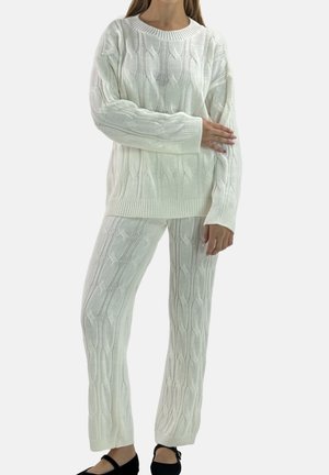 Hvid cable-knit trøje og matchende bukser, med et tekstureret mønster, løs pasform og ribstrikkede manchetter ved håndled og ankler.