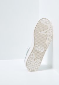 Sneaker blanche avec semelle en caoutchouc, texture lisse et accents gris. Caractéristiques d'une semelle extérieure nervurée et à motif, ainsi qu'un logo en relief.