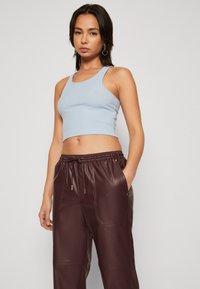 Lyseblå ribbet crop-top med rund hals, kombinert med mørk burgunder faux-lær joggebukser med elastisk midje og lommer.