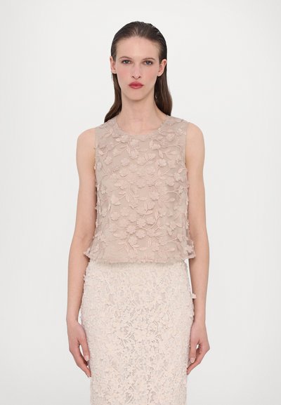 Haut en dentelle florale beige avec texture superposée, col rond et sans manches, associé à une jupe en dentelle assortie.