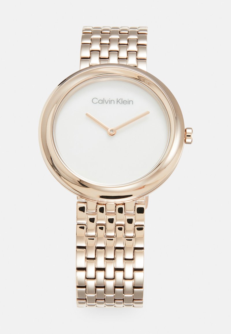 Reloj de metal color oro rosado con caja redonda, esfera blanca y marcadores de hora simples. Cuenta con una correa de eslabones con un acabado pulido.