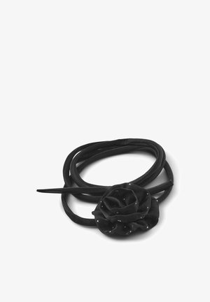 Accessorio per capelli nero che presenta una rosa in tessuto con dettagli argentati, circondata da un lungo nastro nero liscio.