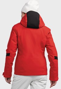 Rote wasserfeste Jacke mit schwarzem Kapuzenbesatz. Zu den Merkmalen gehören ein taillierter Schnitt, lange Ärmel und verstellbare Manschetten. Glatte Textur.