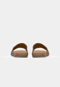 Sandali slide in pelle marrone scuro con soletta imbottita color beige e suola testurizzata; apertura sul retro e design minimalista.