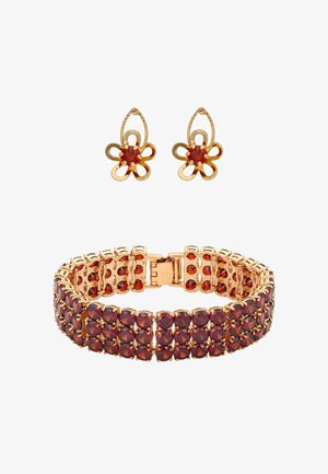 Bransoletka w kolorze złota z czerwonymi kamieniami ułożonymi w klastery; dopasowane złote kolczyki w kształcie kwiatów z czerwonymi środkami i ażurowymi płatkami.