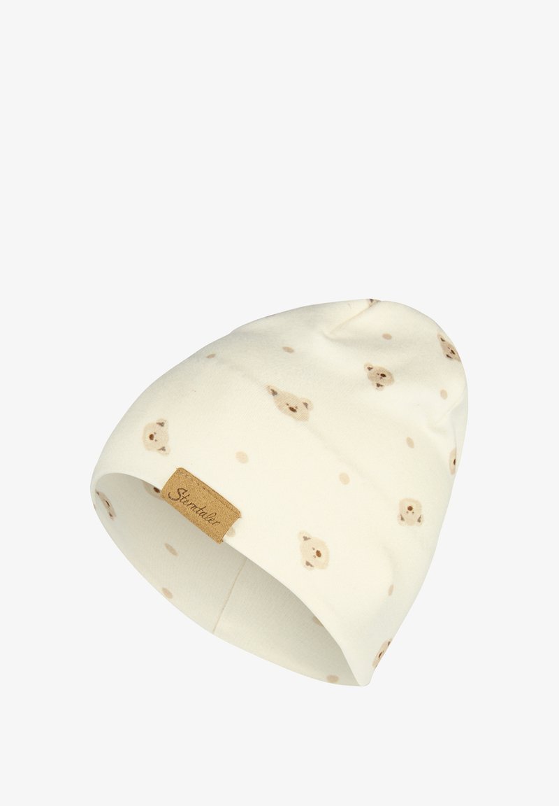 Weißer Strickmütze mit einem Muster aus hellbraunen Bärenköpfen und beigen Punkten, mit einem kleinen braunen Etikett an dem Bündchen.