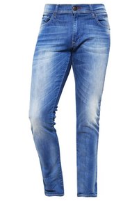 Úzké modré džíny z denimu s vybledlým efektem, pět kapes a zapínáním na zip. Má jemné žíhání a kontrastní švy.