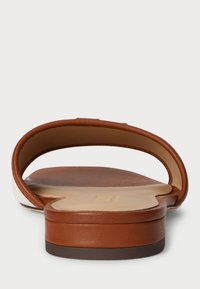 Brązowe skórzane klapki z zaokrąglonym paskiem, płaską podeszwą i gładką teksturą; podeszwa ma subtelne obcasy i minimalne zdobienia.