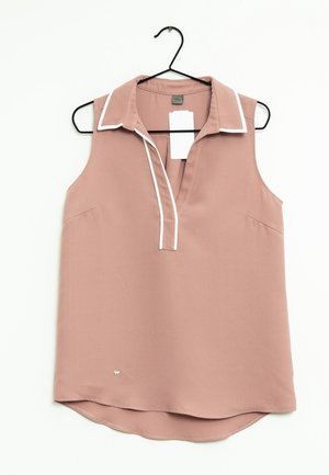 Różowa, bezrękawnikowa bluzka w kolorze przytłumionego różu z białym obszyciem na kołnierzyku i plisach, wisząca na czarnym wieszaku na białym tle.