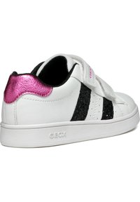 Sneaker bianca con strisce nere glitterate, accentuazione metallica rosa sul tallone, cinturino in Velcro, suola bianca testurizzata e logo "GEOX" sul lato.