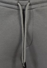 Pantalones de chándal grises con una tela texturizada, con cintura ajustable y bolsillos laterales. Diseño simple enfocado en la comodidad y la funcionalidad.