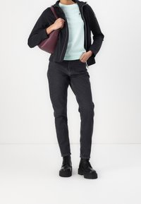 Svart zip-up jacka, ljusgrön tröja, svarta jeans och svarta platåstövlar. Tillbehören inkluderar en vinröd axelväska.