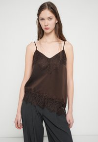 Brun silkesplastrong med V-hals, med intrikat blonderdetalj ved kanten. Tynne, justerbare stropper kompletterer den løse passformen.