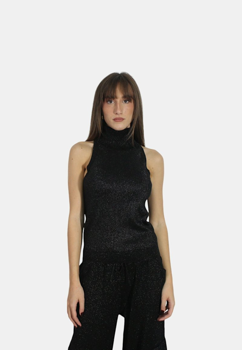 Top nero senza maniche con collo a lupetto e finitura scintillante, design aderente e texture morbida, abbinato a pantaloni neri larghi.