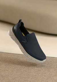 Mornarice klizne cipele napravljene od prozračnog mrežastog materijala s laganom bijelom potplatom. Imaju teksturiranu gornjište i traku za povlačenje na peti za jednostavno oblačenje.