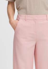 Light pink tailored trousers in a smooth fabric, featuring side pockets, a straight cut, and subtle vertical stripe details.