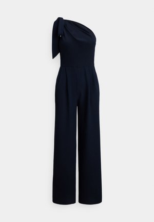 Marinblå jumpsuit med axelband, tillverkad av mjukt tyg, med knytdetalj vid axeln och vida ben med veck.