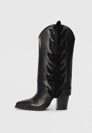 Stivale da cowboy in pelle nera con punta affusolata, decorato con un motivo di foglie in strass neri lungo il gambale. Tacco a blocco massiccio.