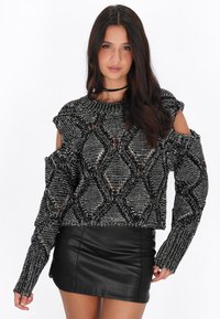 Maglione bianco e nero con spalle scoperte e un motivo a rombi testurizzato. Presenta maniche lunghe e un design corto. Abbina a una gonna di pelle nera.