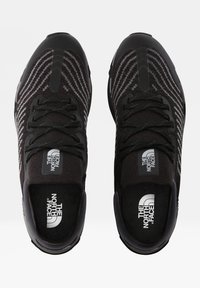 Svarta sportiga sneakers med en texturerad stickad ovandel som har horisontella ränder. Rundad tå, vadderad plös och logotypdetaljer på plösen.