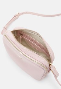Borsa a tracolla rosa testurizzata con cerniera dorata, due scomparti interni e tracolla regolabile. Fodera liscia e piccoli dettagli hardware.