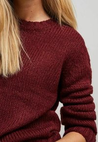 Bordowy sweter z dzianiny z okrągłym dekoltem, teksturową tkaniną i prążkowanymi mankietami, prezentujący luźny krój i średnią grubość.