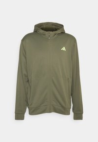 Sweat à capuche zippé vert olive en tissu lisse, avec une capuche, deux poches avant et un petit logo vert citron sur la poitrine gauche.