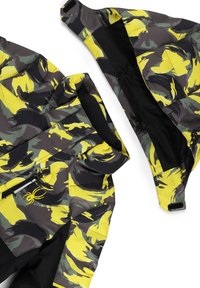 Giacca mimetica nei toni grigio, giallo e nero. Presenta una tasca con zip e un logo a forma di ragno. Realizzata in un materiale leggero e liscio.