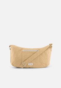 Sac bandoulière beige clair en tissu texturé, avec une poche zippée en métal argenté, une bandoulière ajustable et une étiquette portant le nom de la marque.