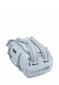 Borsa da viaggio blu chiaro realizzata in tessuto resistente, con manici imbottiti, scomparti con zip e il logo Thule sul lato.