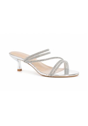 Sølv åben tå sandal med kitten heel med fire tynde rhinsten-remme over foden og en beige indlægssål på hvid baggrund.