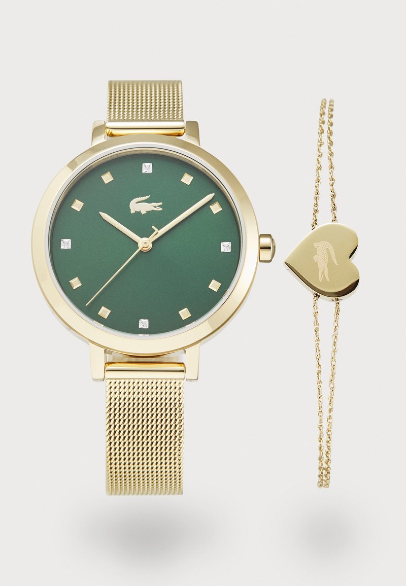 Zlata mrežasta ura z zelenim mat ure, zlatimi urobniki in majhnimi diamanti. Vključuje nežno zlatih srčnih zapestnico.