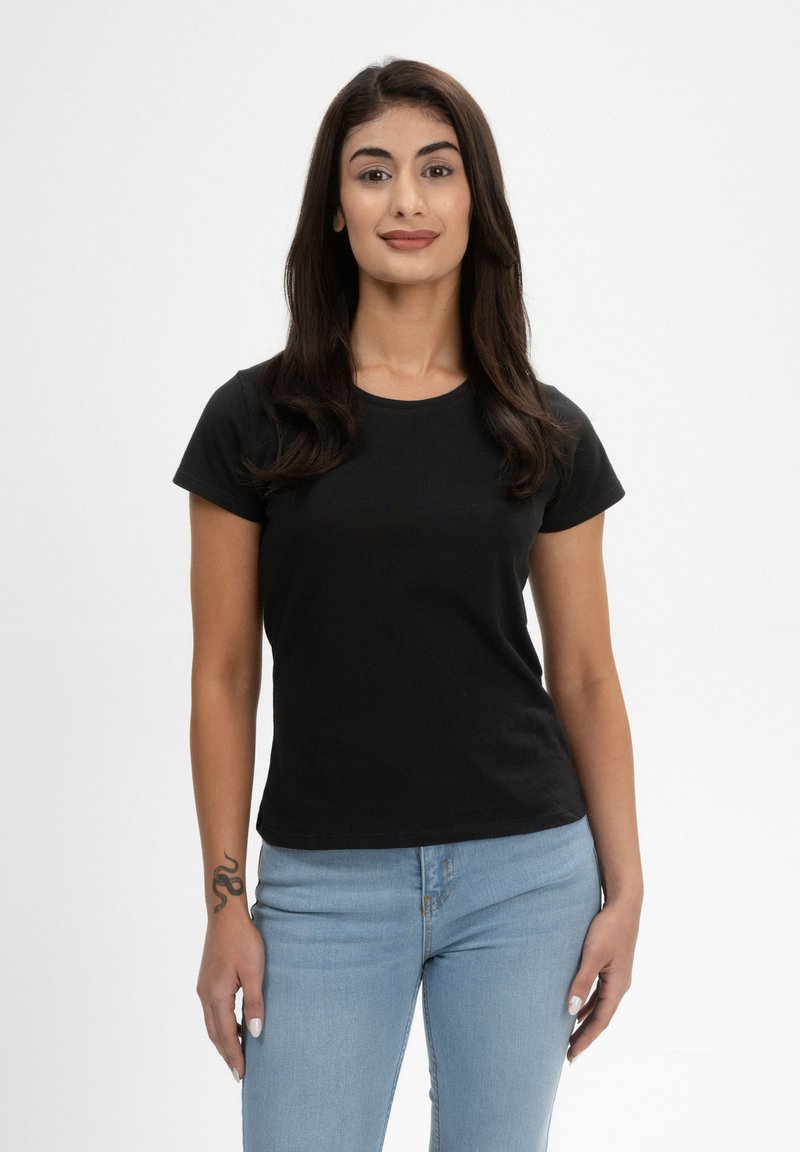 Schwarzes Baumwoll-T-Shirt mit kurzen Ärmeln, rundem Halsausschnitt und schmaler Passform, kombiniert mit hellblauen Jeans. Vor einem schlichten weißen Hintergrund präsentiert.