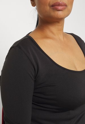 Black long-sleeve top with a wide scoop neckline. Fabric appears smooth and stretchy, fitting closely to the body.