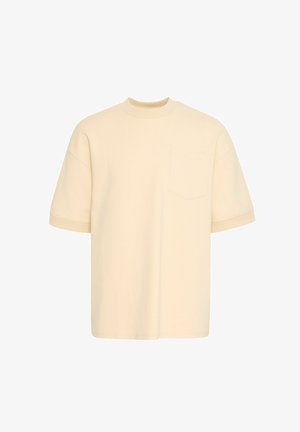 T-shirt surdimensionné de couleur crème avec un col rond, des manches courtes et une poche poitrine. Fabriqué en tissu doux avec une texture lisse.