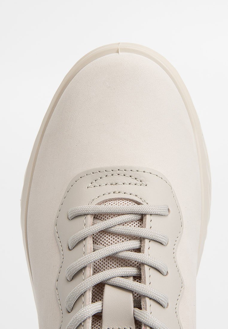 Jasno-beżowe sneakersy o gładkim, zamszowym wykończeniu, okrągłym czubku i szarych sznurówkach. Posiadają siateczkowe detale po bokach, które zapewniają oddychalność.