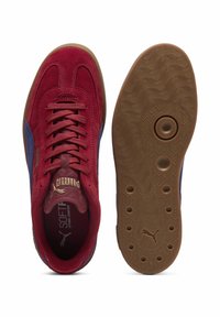Puma sneakers i rød suede med blå accenter, featuring gummisål og struktureret dæk. Guld logo på tungen, snørebånd i matchende farve.