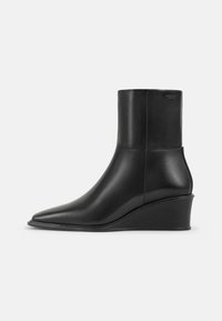 Černé kožené kotníkové boty s špičatou špičkou a klínovým podpatkem. Hladká textura, přiléhavý design, žádné viditelné kování nebo vzory.