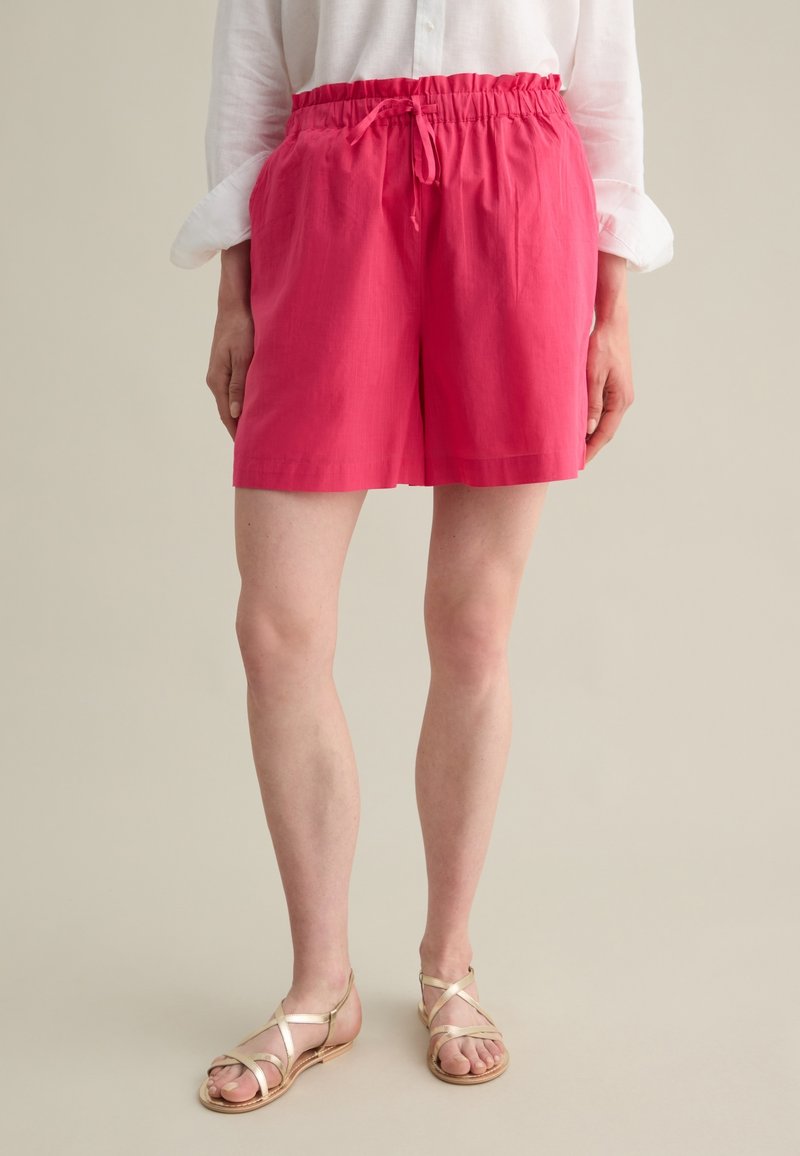 Pantaloni corti leggeri rosa con vita elastica e coulisse, caratterizzati da una vestibilità comoda e una texture liscia.