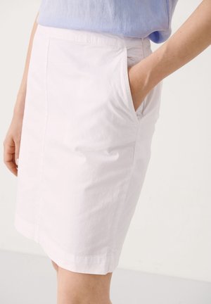 Jupe en coton blanc avec une coupe droite, poches latérales et une longueur juste au-dessus du genou. Texture lisse avec un minimum de détails.