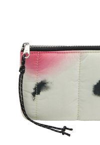 Padded worek z czarnym zamkiem błyskawicznym, materiał w kolorze czerwonym i kremowym z czarnymi wzorami w kształcie plam atramentowych oraz czarnym sznurkiem z węzłami.