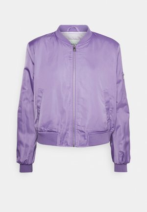 Veste bomber lavande avec fermeture éclair frontale, col, poignets et taille côtelés, deux poches latérales et une poche zippée sur la manche.
