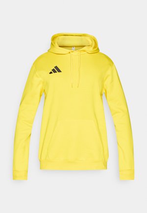 Żółta bluza z kapturem, przednią kieszenią, sznurkiem w kapturze oraz czarnym logo Adidas na lewej piersi. Gładka tkanina i prążkowane mankiety.
