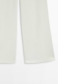 White pants legs with straight hems, shown from mid-thigh down, against a plain white background.