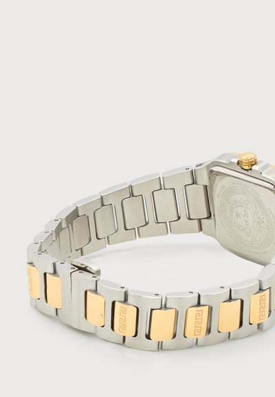 Sidabrinės metalinės laikrodžio apyrankės su auksinėmis stačiakampėmis intarpomis ir graviruotais raštais, pritvirtintos prie kvadratinio laikrodžio korpuso su auksine karūnėle.