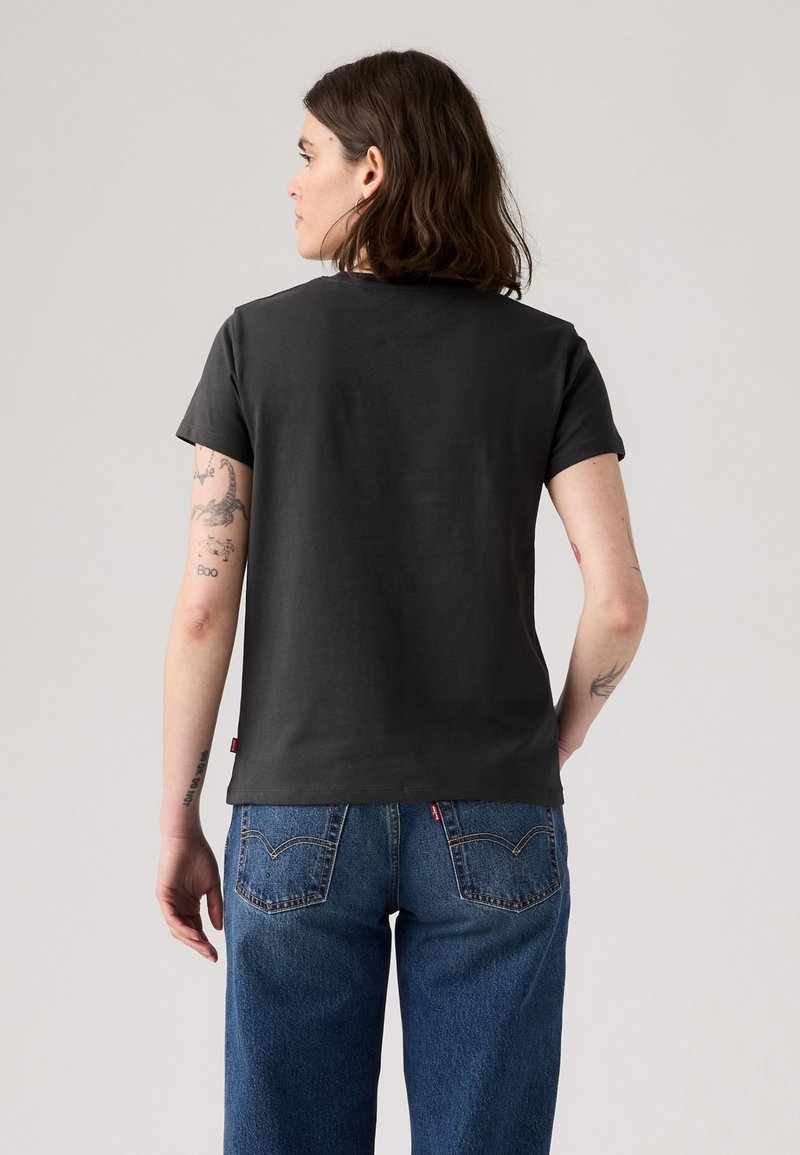 Czarny bawełniany t-shirt z krótkim rękawem, okrągłym dekoltem, prosty design. Połączony z niebieskimi dżinsami z kieszeniami z tyłu z detalem przeszycia.
