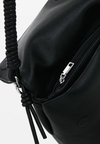 Czarna skórzana torebka o teksturowanej powierzchni, z zamkiem błyskawicznym i detalami w postaci skręconego paska. Posiada błyszczący srebrny zamek i okrągły akcent.