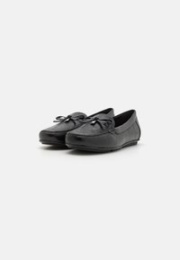 Mocassins en cuir noir avec une finition texturée, bout rond et un nœud décoratif à l'avant. Semelle profil bas pour le confort.