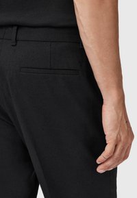 Pantaloni neri realizzati in tessuto testurizzato, dotati di una tasca posteriore piatta e una vestibilità slim, con una vita liscia e dettagli di cucitura discreti.